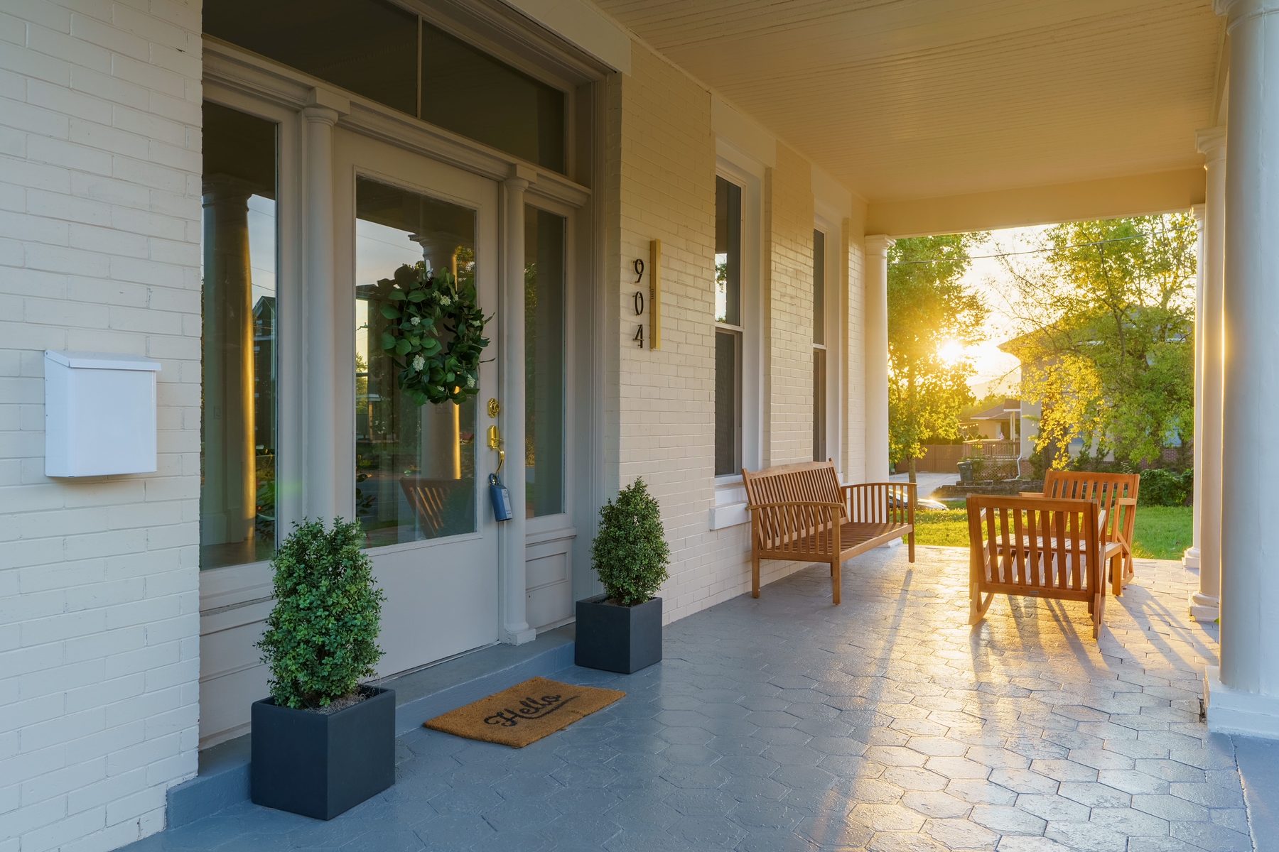 Wraparound porch of a restored historic home glowing in golden evening light