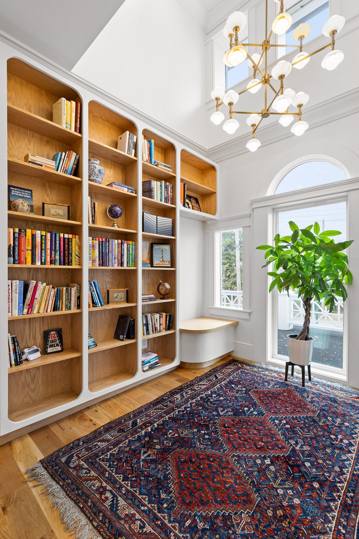 Floor-to-ceiling custom oak library shelving lit by a chandelier