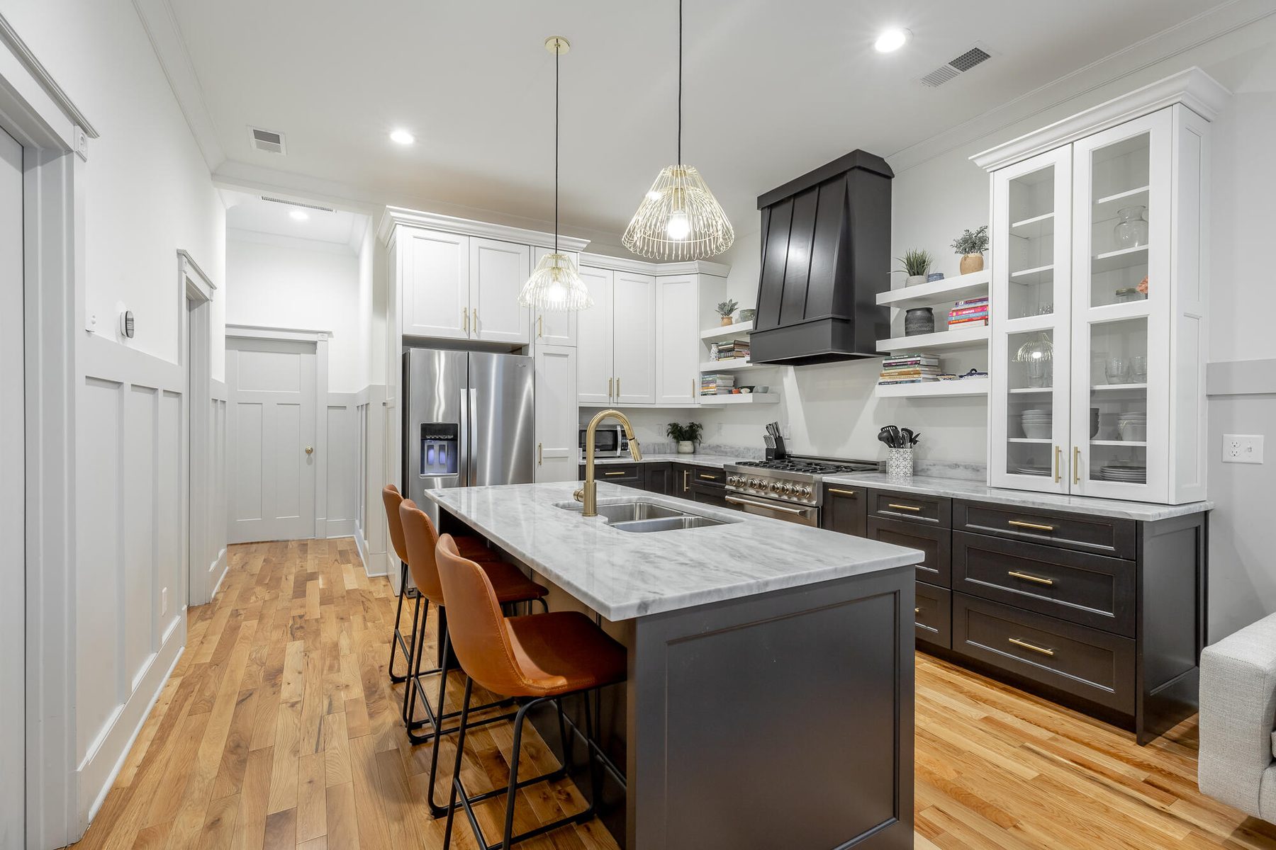 Charcoal kitchen island with leather bar stools and marble counters, opening to the living room