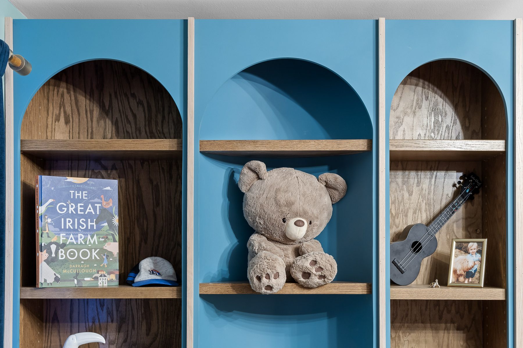 Custom arched built-in shelving in birch and blue, built into a child's bedroom wall